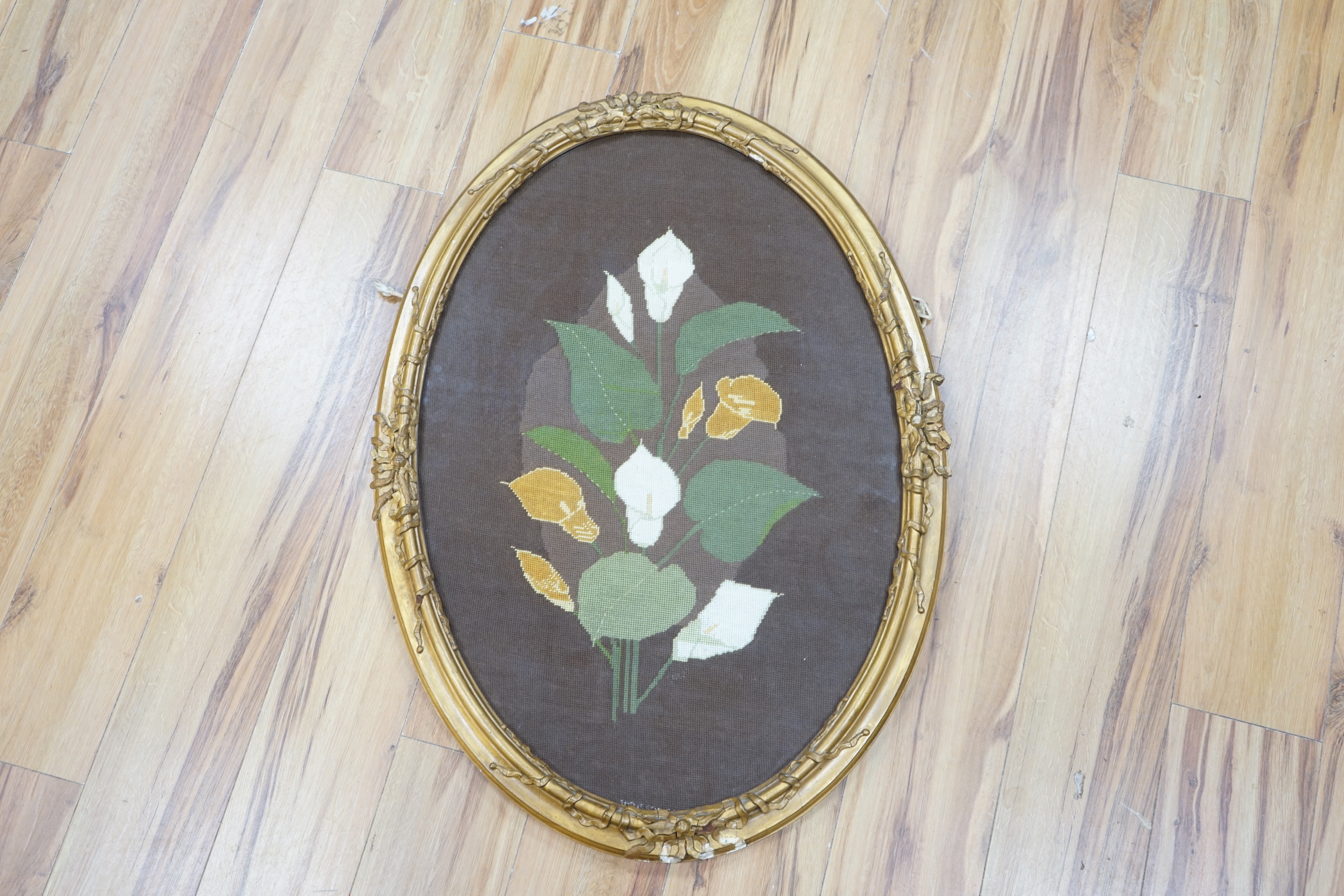 An oval framed cross stitch embroidery of a lily, indistinctly signed and dated, 80cm x 54cm